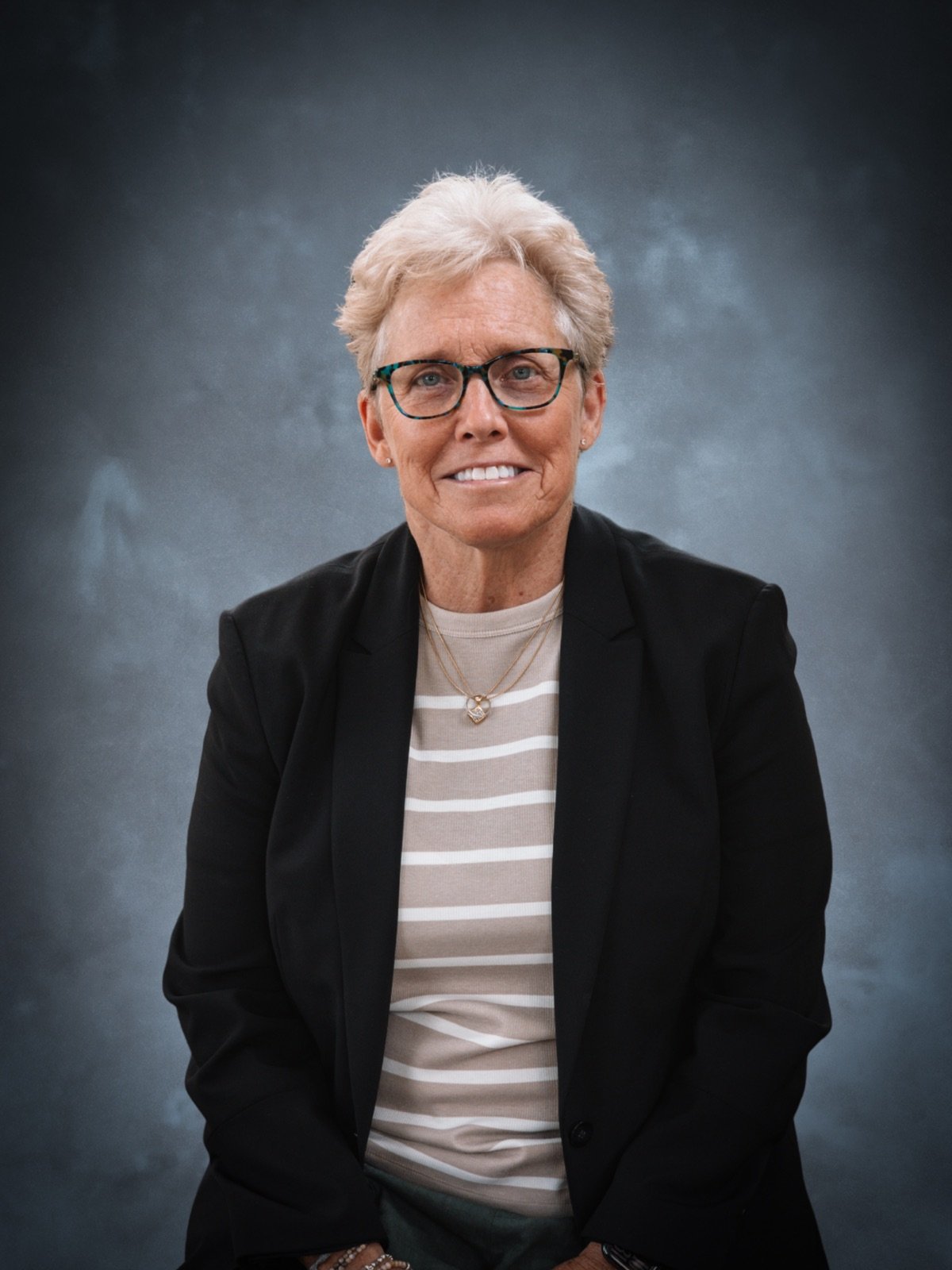 Media kit headshot of Debra Shumar, studio portrait against a dark background.